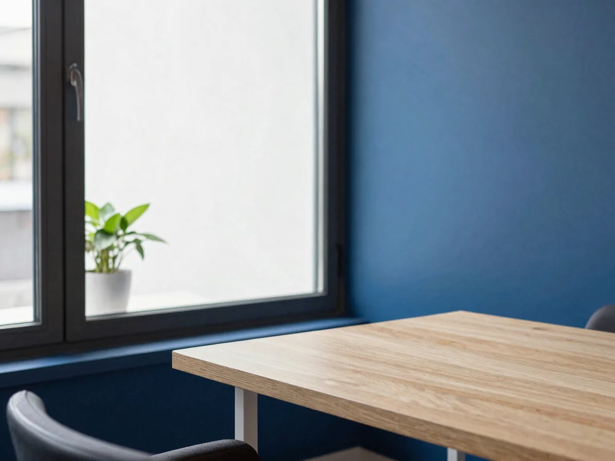 Vue large et douce d’un espace de consultation sobre, fenêtre à lumière naturelle, plante ordinaire et table en bois cla